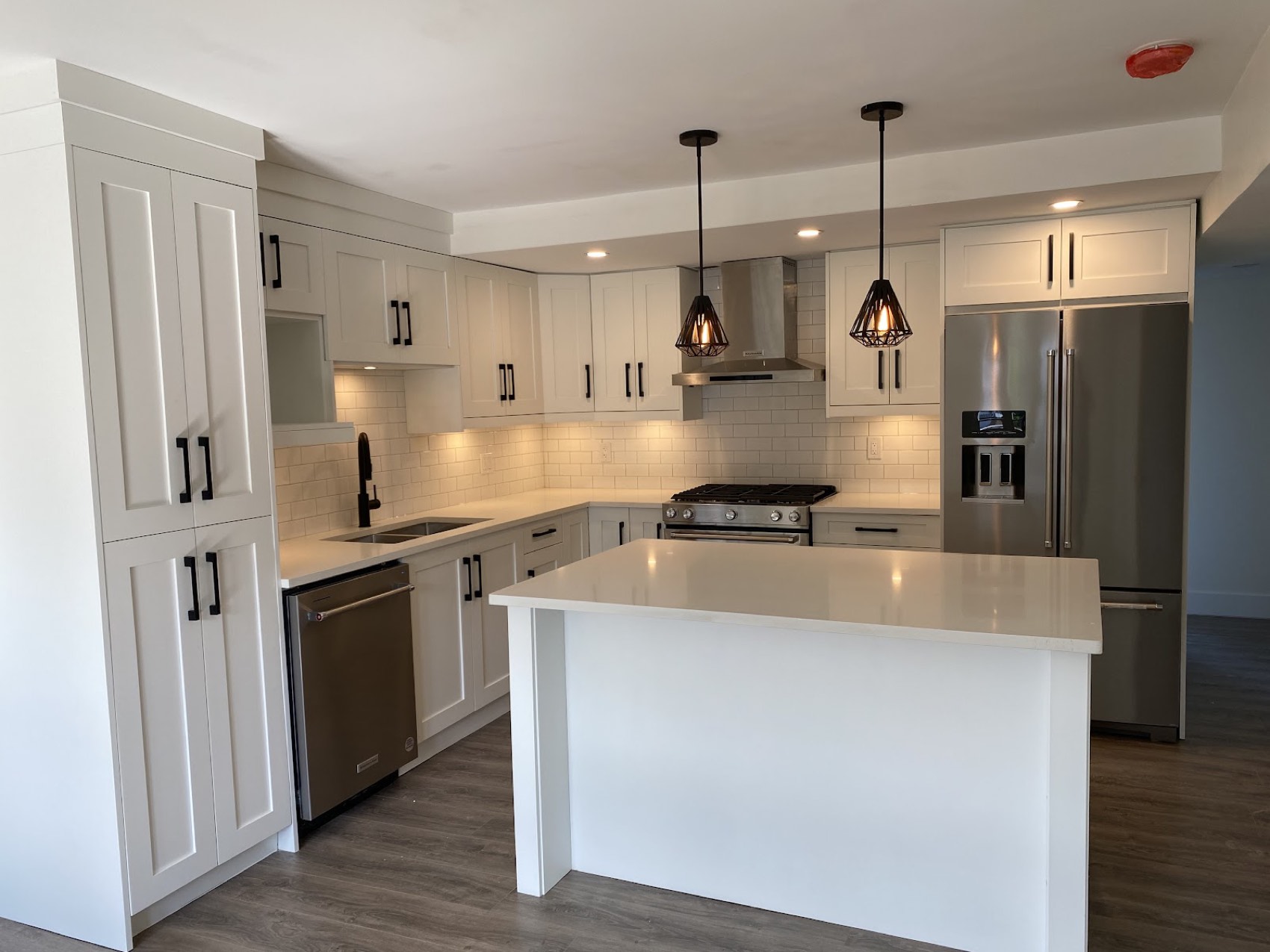 Renovated kitchen with white cabinets, island and pendant lighting