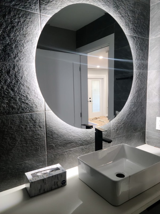 Bathroom with a backlit round mirror above a stone basin
